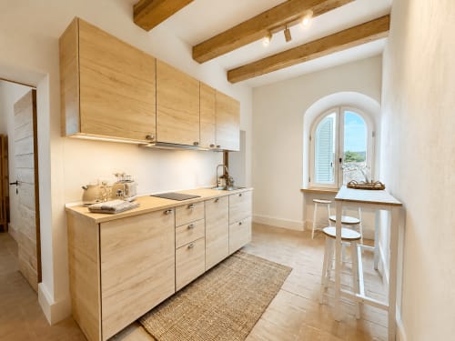 Cucina moderna in legno con travi a vista, finestra ad arco e bancone al Tuscan Townhouse B&B di Montemassi