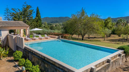 Villa de lujo con piscina en Artà, Mallorca: tumbonas, terraza de piedra y olivares con vistas a montañas