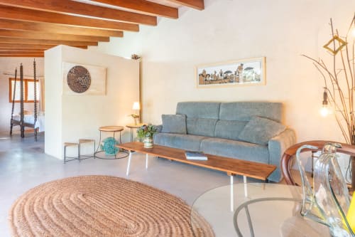 Sala de estar moderna en Massa Properties en Artà con sofá gris, vigas de madera y alfombra de yute redonda