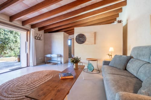 Sala de estar rústica moderna en Massa Properties, Artà, con vigas de madera vista, cómodos asientos y vistas a la terraza