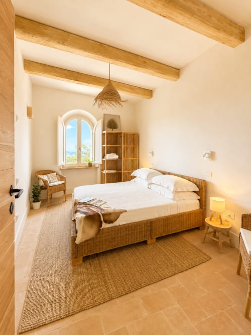 Bellavista Suite bedroom in Tuscan Townhouse, Montemassi with beamed ceilings, wicker bed, arched window with landmark views