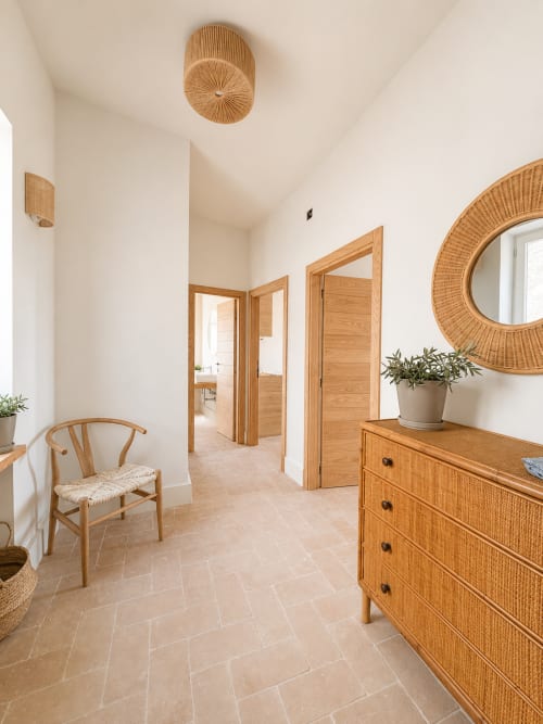 Bright hallway in Bellavista Suite at Tuscan Townhouse with wooden doors, wicker mirror, dresser, and herringbone tile