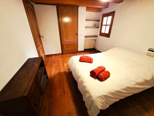 Espacioso dormitorio doble en L'Orri Rectoria Nova de Campelles con vigas de madera, suelo de parqué y toallas de bienvenida rojas