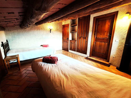Acogedora habitación doble rústica en L'Orri Rectoria Nova con vigas de madera vista, suelos de barro y puertas tradicionales