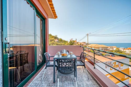 Terraço com vista para o oceano na Villa Amore, Madeira, com mesa de jantar com vista para o mar, jardim e montanhas