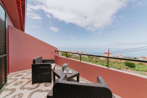 Terraço com móveis de vime preto com vista para o oceano e montanhas na Villa Amore, Portugal