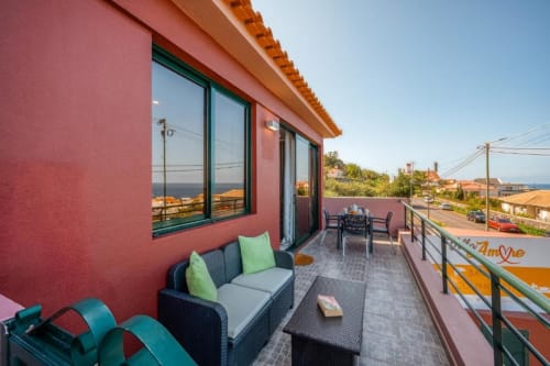 Terraço moderno da Villa Amore com vista para o mar, zona de estar e área de refeições em Paul do Mar, Portugal