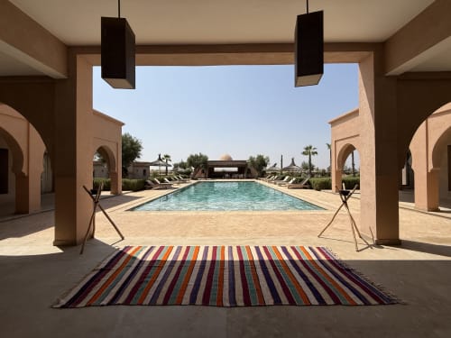 Terrasse élégante avec piscine à Villa Rêve D'ahlam, tapis rayé, architecture marocaine et transats à Jbilate