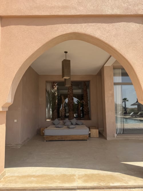 Alcôve voûtée de chambre à Villa Rêve D'ahlam à Jbilate avec lit en bois, décor de palmiers et vue sur la piscine