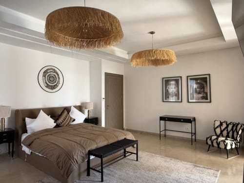 Chambre moderne à la Villa Rêve D'ahlam à Jbilate avec tête de lit marron, luminaires suspendus tressés et mobilier contemporain.