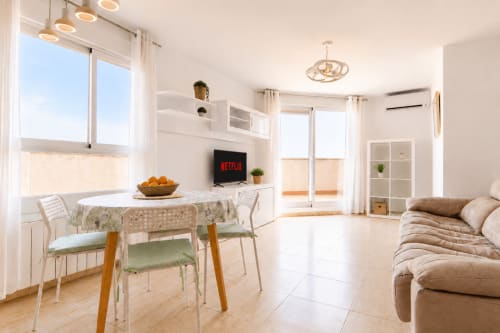 Luminoso salón moderno en Calpe con comedor, sofá, televisor y vistas al balcón