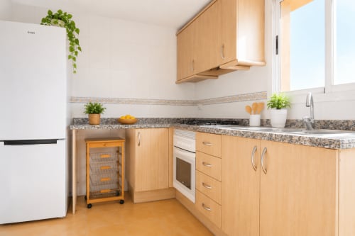 Cocina moderna en apartamento Riurau Home, Calpe con muebles de madera, encimeras de granito y electrodomésticos de acero inoxidable