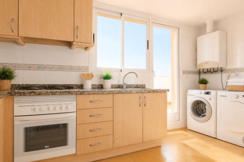 Cocina moderna con muebles de madera, encimera de granito y lavadora-secadora en apartamento de Calpe
