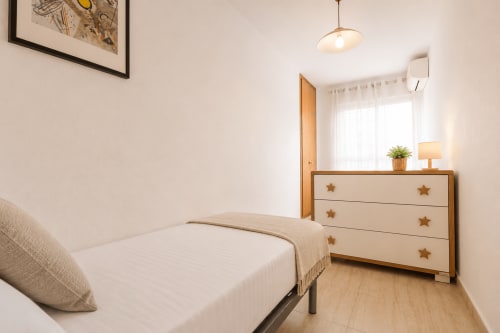 Dormitorio luminoso en apartamento Riurau Home, Calpe con cama individual, cómoda de madera con tiradores de estrella y vistas a las montañas