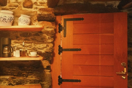 Cocina rústica de piedra en Casa Grande de Covas con armario rojo de madera, estantes de madera y decoración tradicional en Taboada, Lugo