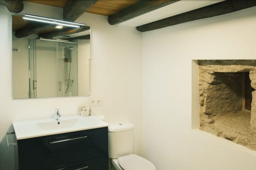 Baño moderno en Casa Grande de Covas con tocador negro, espejo y nicho de piedra vista en Taboada