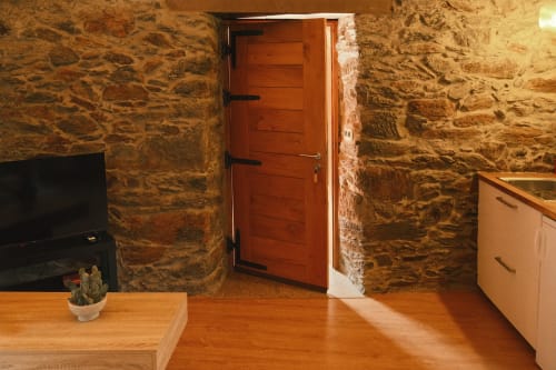 Interior rústico de piedra en Casa Grande de Covas, Taboada, con puerta de madera y chimenea