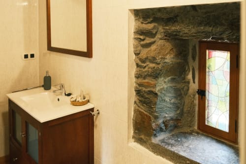 Baño moderno en Casa Grande de Covas en Taboada con mueble de madera, entrada de ducha en piedra e iluminación cálida