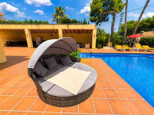Luxury poolside daybed at Casa Emilia villa in Moraira with resort-style amenities and sparkling blue pool