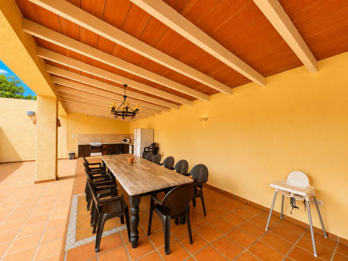 Spacious dining room in Casa Emilia villa with wooden beamed ceiling, yellow walls, and large wooden table with black chairs