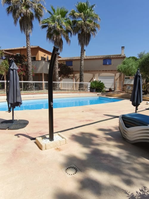 Espace piscine Au bon vivre à Vives avec palmiers, transats et maison en terre cuite