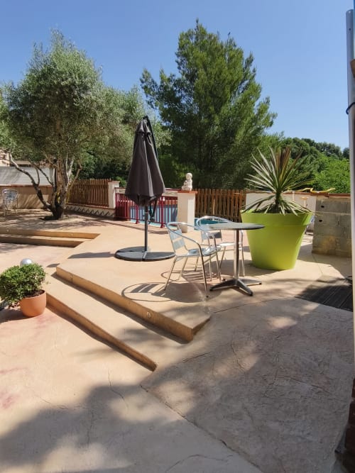 Terrasse ensoleillée à l'Au bon vivre B&B à Vives avec parasol, coin détente et jardin verdoyant