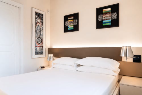 Camera moderna al B&B Pellicano con letto bianco, testata marrone, arte murale contemporanea e vista mare a Reggio Calabria