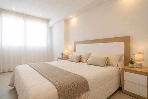 Luminoso dormitorio moderno en Riurau Home Calpe con cama de madera, sábanas blancas y vistas al mar