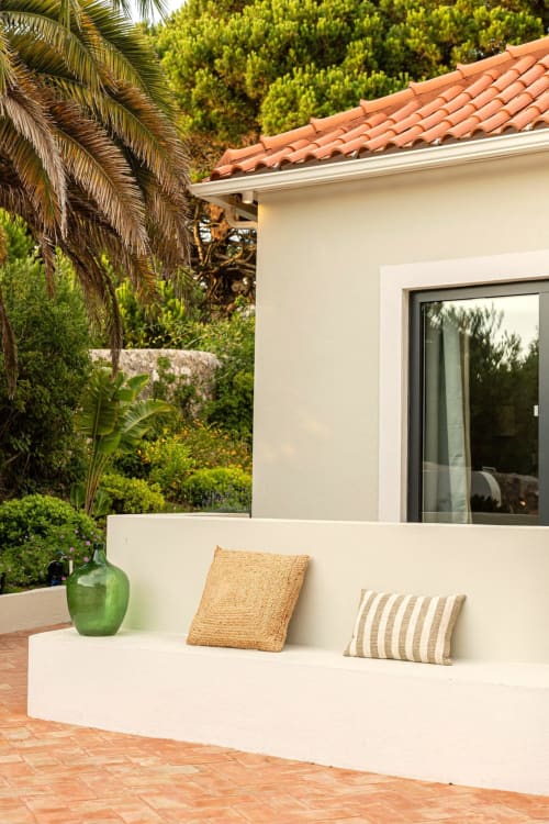 Modern villa terrace at Sea'Ya Casa Pavão with white built-in seating, decorative pillows, green vase, and lush garden views