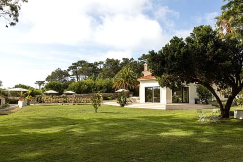Sea'Ya Casa Pavão villa in Colares with manicured lawn, white modern building, palm trees, and terrace seating area