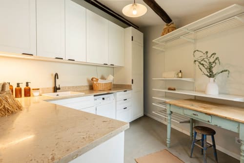 Modern kitchen and dining area in Sea'Ya Casa Pavão villa, Colares, featuring white cabinetry, stone countertops, and open