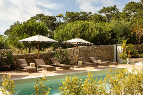 Sea'Ya Casa Pavão villa pool terrace with loungers, umbrellas, and stone walls overlooking lush gardens in Colares, Portugal