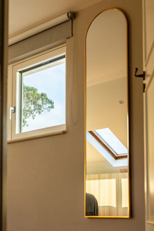 Modern mirror with gold frame in Sea'Ya Casa Pavão villa, reflecting skylight and interior space
