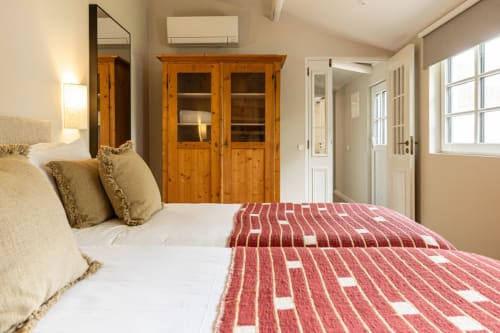 Bright bedroom at Sea'Ya Casa Pavão villa in Colares with double beds, wooden wardrobe, and natural light from windows
