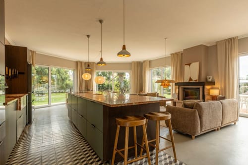 Modern villa kitchen and living area with island seating, pendant lights, fireplace, and garden views at Sea'Ya Villas in
