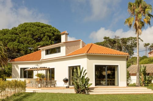 Sea'Ya Casa Pavão villa in Colares with white facade, orange roof, wooden terrace, and manicured garden under blue sky