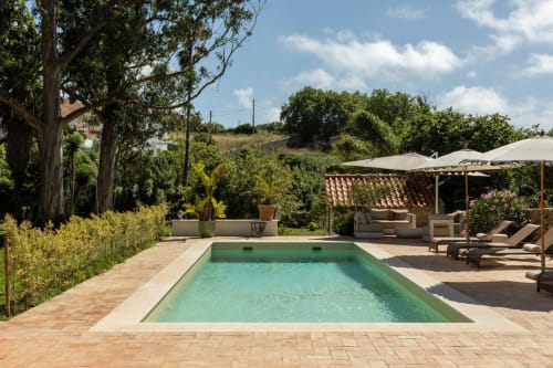 Turquoise rectangular pool at Sea'Ya Casa Pavão villa in Colares, surrounded by terracotta patio, lounge chairs, and lush