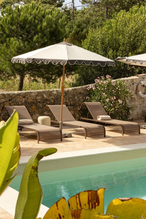 Sea'Ya Casa Pavão villa pool area with lounge chairs, cream umbrella, and lush garden in Colares, Portugal