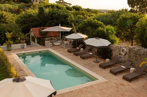 Luxurious pool area at Sea'Ya Casa Pavão villa in Colares with loungers, umbrellas, and Mediterranean landscaping