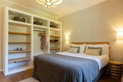 Modern bedroom at Sea'Ya Casa Pavão villa in Colares with built-in shelving, wooden bed frame, and warm lighting