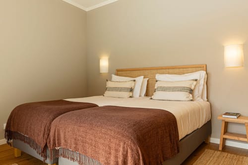 Spacious bedroom at Sea'Ya Villas villa in Colares with wooden headboard, brown throw blanket, cream bedding, and bedside