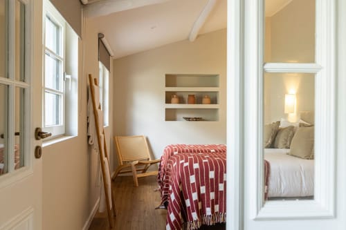 Cozy bedroom at Sea'Ya Casa Pavão villa in Colares with red patterned bedding, wooden chair, built-in shelving, and view to