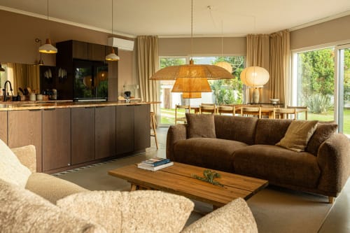 Spacious Sea'Ya Casa Pavão villa living room with brown sofa, wooden table, designer lighting, and open-plan kitchen