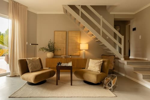 Modern living room at Sea'Ya Casa Pavão villa in Colares with tan curved chairs, staircase, and natural light