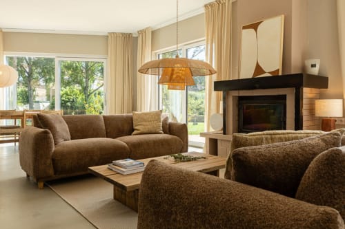 Elegant living room at Sea'Ya Casa Pavão villa with brown sofas, fireplace, pendant lighting, and garden views through large