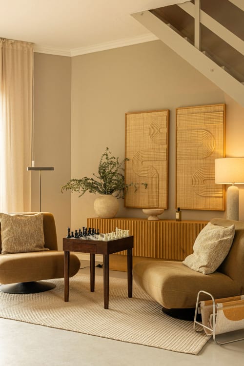 Warm minimalist living room at Sea'Ya Casa Pavão villa with golden armchairs, chess table, and woven wall art in neutral