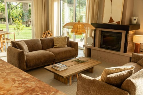 Spacious living room at Sea'Ya Casa Pavão villa in Colares with fireplace, brown sofa, wooden table, and garden views through