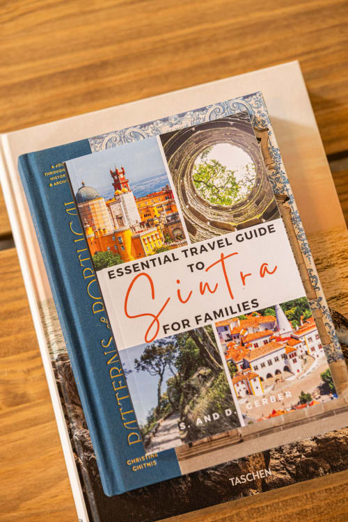Travel guide books stacked on wooden surface at Sea'Ya Villas in Colares, Portugal