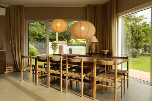 Modern dining room at Sea'Ya Casa Pavão villa in Colares with wooden chairs, paper lantern lights, and garden views through