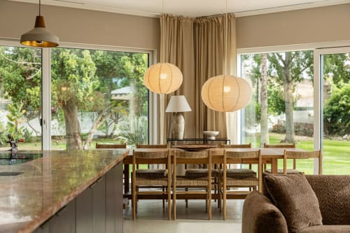 Modern villa dining room at Sea'Ya Casa Pavão with wood chairs, pendant lights, and garden views through large windows in